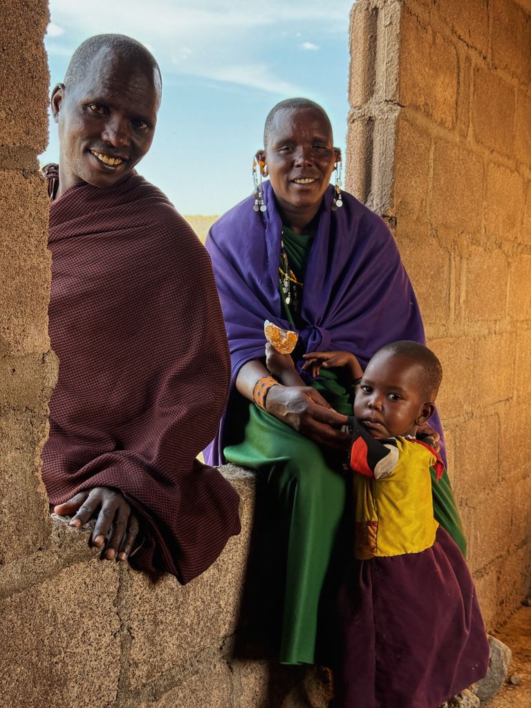 A Maasai family in colorful traditional attire inside a rustic building in Kilimanjaro, Tanzania.
