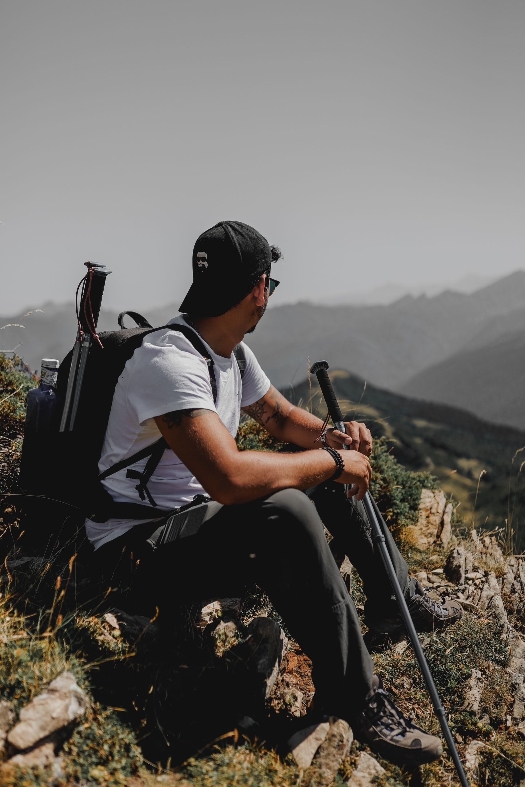 A man resting on a mountain trail, enjoying the scenic view with backpack and hiking gear.