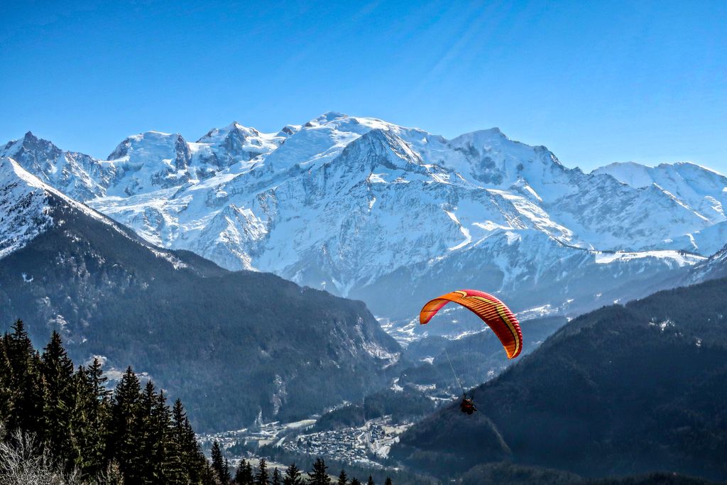 A thrilling paraglider soars over Mont Blanc in Passy, capturing the stunning winter mountain scenery.