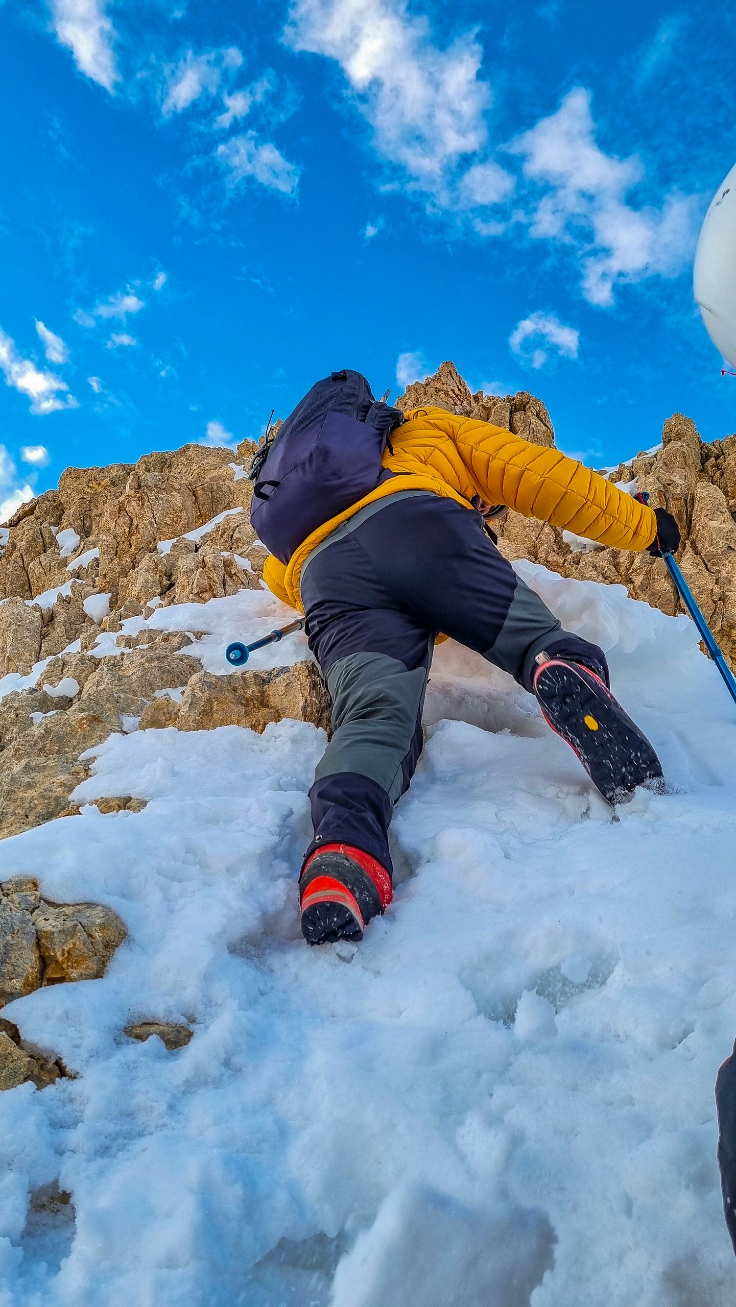 Back view of a climber ascending a snowy mountain, capturing the thrill of adventure and winter exploration.