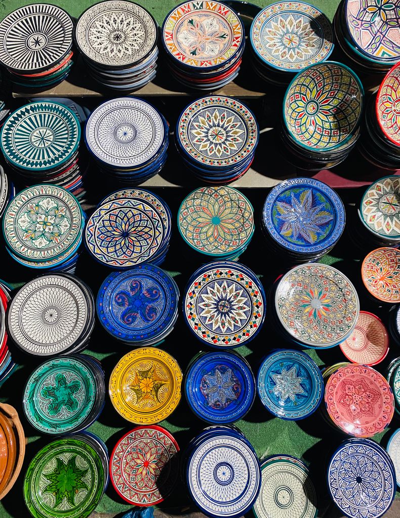 Colorful handmade Moroccan ceramic plates with Oriental patterns on display in Marrakech market.