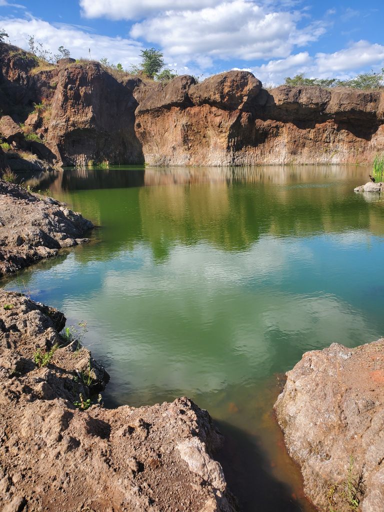 Lush green lake amidst rocky landscape in Moshi, Tanzania.