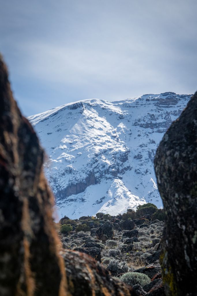 Majestic snow-covered mountain peak framed by rocky foreground.