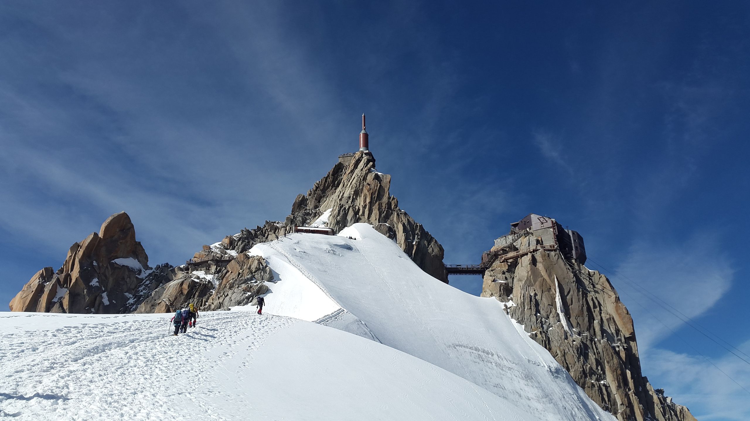 Mountaineers climbing Aiguille du Midi in the French Alps during winter, showcasing adventure and scenic views.