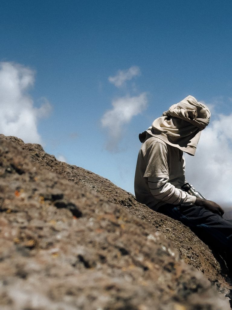 Solitary hiker rests on a rock with scenic skies at Mount Kilimanjaro, Tanzania.