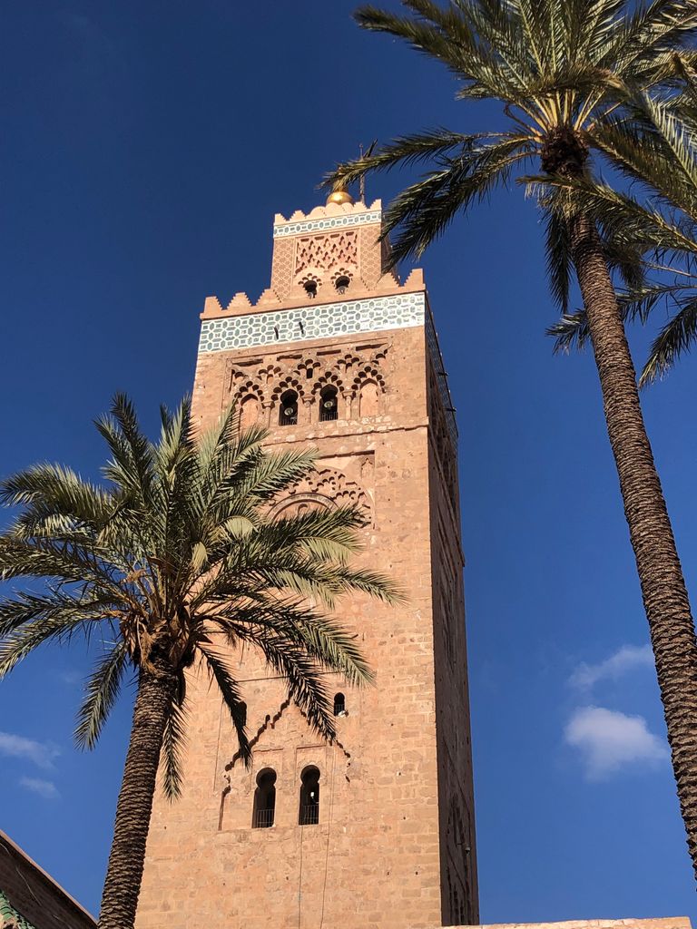 Stunning view of Koutoubia Mosque minaret and palm trees under a clear blue sky in Marrakech.
