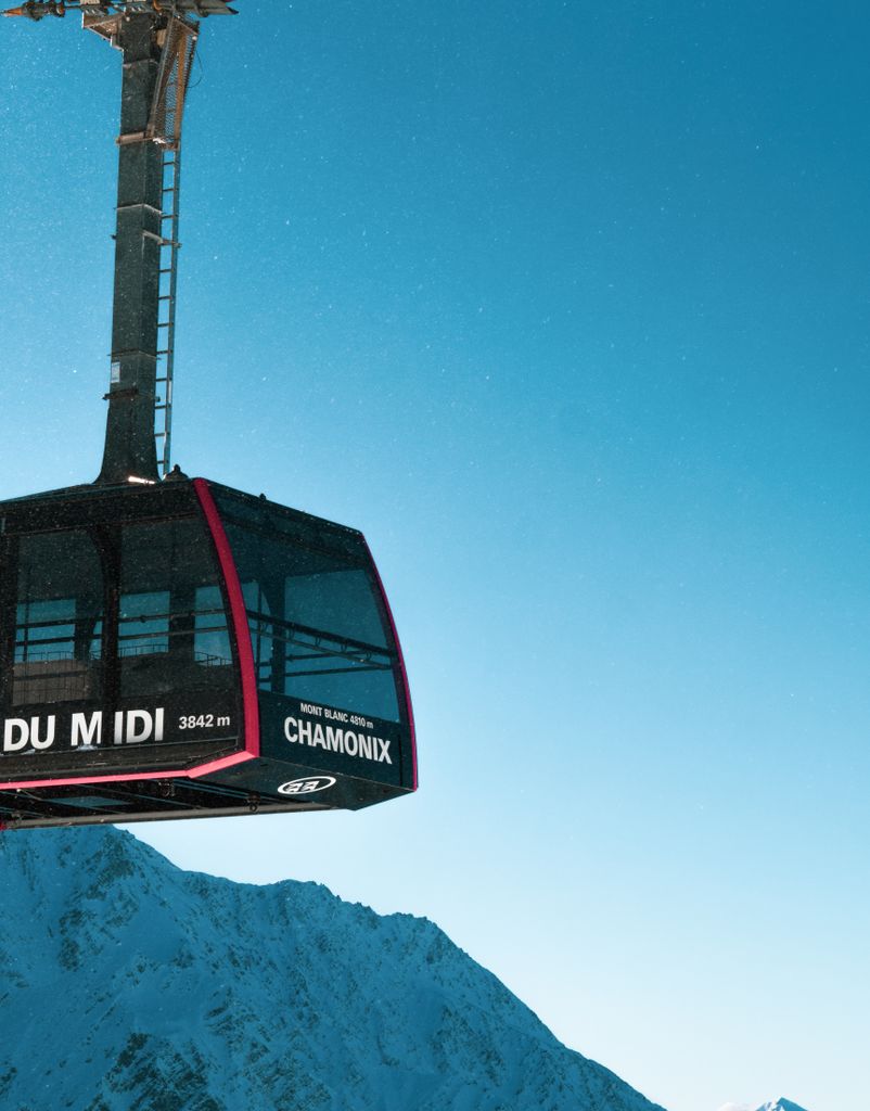 Stunning view of the Chamonix cable car soaring over snow-covered peaks under a clear blue sky.