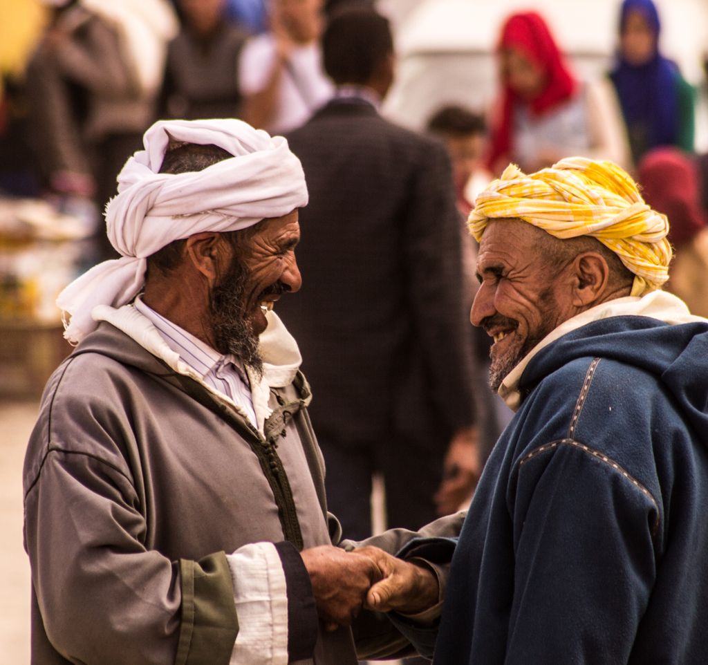 Two men sharing a joyful moment in a bustling Marrakech street, capturing local life.